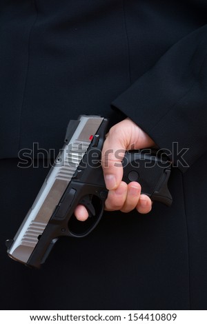 Close up with woman in business suit hold a pistol to dark suit