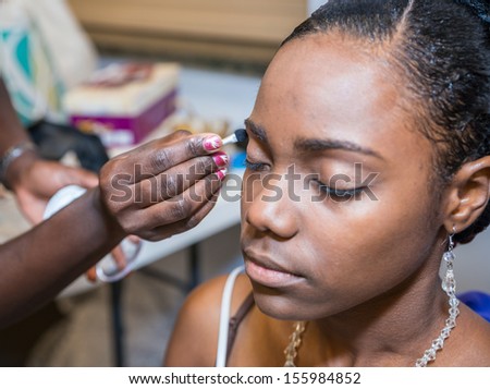 Young woman putting on her eye liner with help