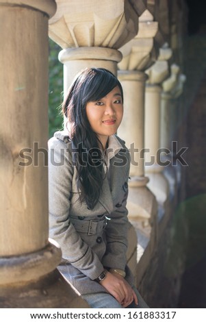 Young woman sitting next to a row of stone pillars