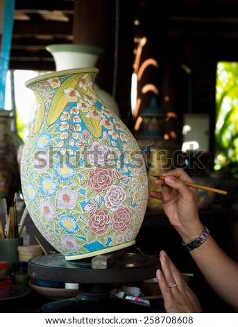 Somebody is painting  Flower on vase with paintbrush
