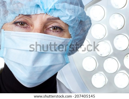 Senior woman surgeon in cap and face mask in surgery room interior