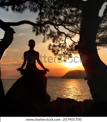 Female silhouette meditation on sunrise