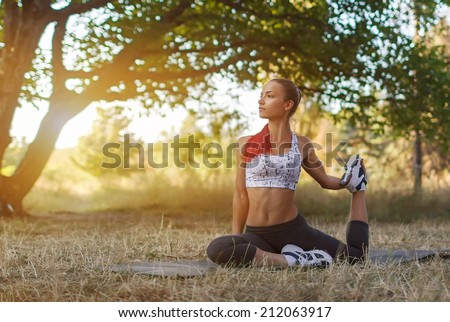Warming-up. Beautiful young caucasian woman in fitness wear doing exercises in a park