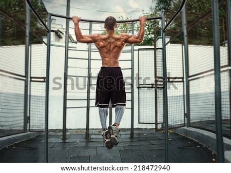 athlete doing pull-up on horizontal bar.Mans fitness at the stadium