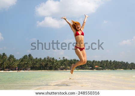 girl in a bathing suit jumping on the beach with happiness