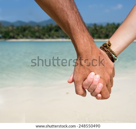 man and woman holding hands on the beach close-up