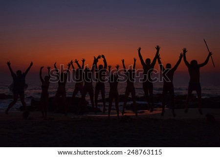 People silhouettes with raised hands in goa sand each with sunrise gradient on background