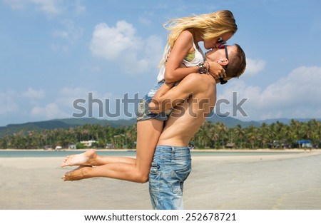 Couple in love on the beach. Guy raised his girlfriend and she kisses him