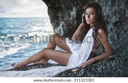 Portrait of beautiful sexy girl in wet white shirt relaxing on the sea