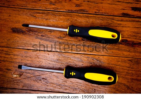 Pair of New Hard Black Yellow Screw Driver on Wood Table, Rustic Style.