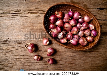 Group of String Fresh Red Onion Unpeeled with Woven Basket kitchenware harvest from farm garden on Wood Table Background, Rustic Still Life Style.