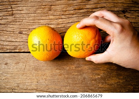 Hand Holding (Pick, Choose,Select,Harvest) Fresh Orange on Wood Table Desk Background, Rustic Style.