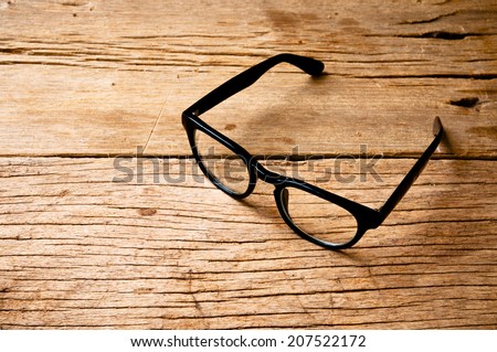 Clear Eyeglasses Glasses with Black Frame Fashion Vintage Style on Wood Desk Background, Rustic Still Life Style.