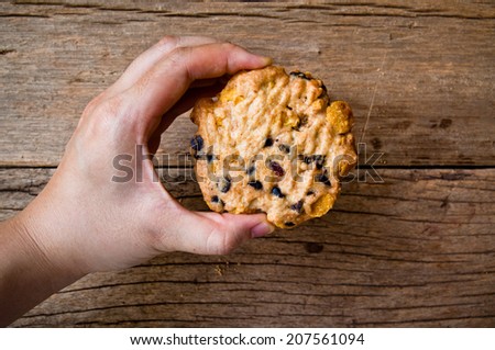 Hand Holding (Cook,Show,Select,Pick) Homemade Bake Chocolate Chip Cookie on Wood Table Background, Rustic Still Life Style.