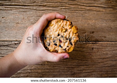 Hand Holding (Cook,Show,Select,Pick) Homemade Bake Chocolate Chip Cookie on Wood Table Background, Rustic Still Life Style.