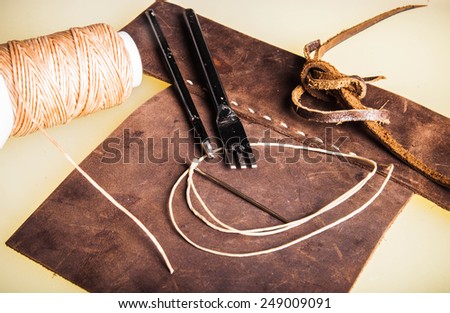Leather Crafting, Handcrafts Work, Handmade Leather Tools with Dark Brown Leather with Wax Cord and Metal tools on hard board workspace.