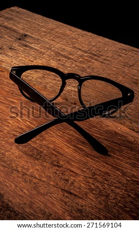 Clear Eyeglasses Glasses with Black Frame Fashion Vintage Style on Wood Desk Background, Rustic Still Life Style.