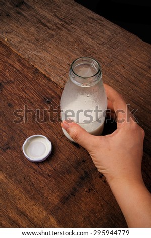 Fresh Milk, Glasses Bottle Opened with Hand Holding. Ready to Drink, Organic Dairy Produce, Concept and Idea of Breakfast on Wood Table Background, Country Rustic Still Life Style. Vertical.