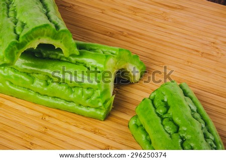 Green Bitter Melon, Bitter Gourd, Bitter Cucumber, Balsam Pear, Sliced Cut. Fresh Organic Harvest on Wood Board and Background. Concept and Idea of Asian Cooking Style.