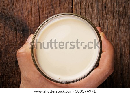 Fresh Milk, in Glasses with Hand Holding. Ready to Drink, Organic Dairy Produce. Concept and Idea of Breakfast, on Wood Table Background. Country Rustic Still Life Style.