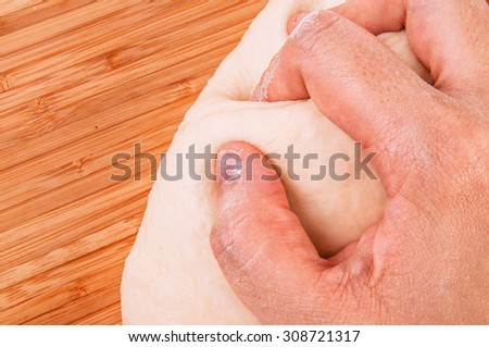 Hand Kneading Dough for Making Bread, Pizza, Pasta and Others Pastry. Concept and Idea of Homemade Fresh Baking and Cooking. Wood Table Background, Still Life Style. Close up.