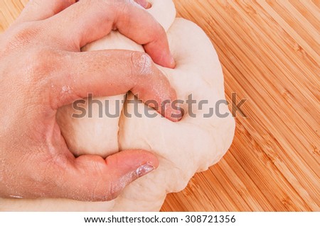 Hand Kneading Dough for Making Bread, Pizza, Pasta and Others Pastry. Concept and Idea of Homemade Fresh Baking and Cooking. Wood Table Background, Still Life Style. Close up.