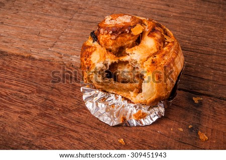 Cinnamon Roll, Almond and Sugar Crispy Top, Eaten with Bite Missing. Homemade Fresh Baked. Wood Background, Country Rustic Still Life Style.