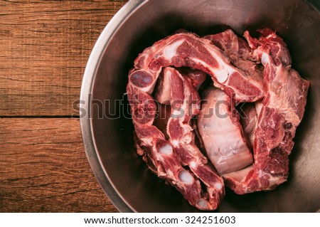 Pork Ribs, Raw. Organic Fresh Meat in Stainless Bowl. Preparation for Cooking or Grill. Wood Background and Textured, Country Rustic Style. Selective Focus.