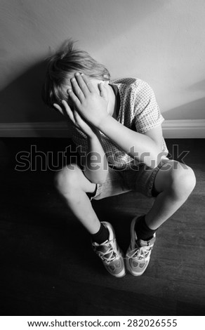 Young Boy covering his face in a curled defensive position