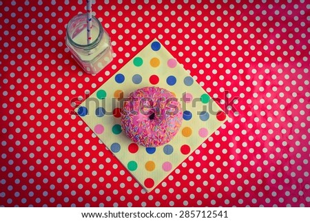 Food to Celebrate - An iced ring doughnut on a spotty napkin and table cloth with a glass of milk