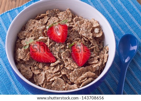 Muesli with strawberries with spoon on a blue napkin
