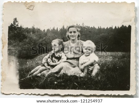 Vintage photo of mother with children sitting on grass (fifties)