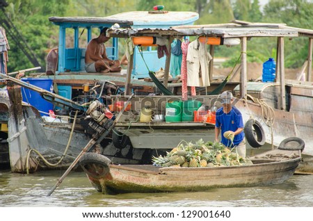CHAU DOC, VIETNAM, JANUARY 4: - Unidentified man sells pineapples from his wooden boat on floating market in Mekong Delta on January 4, 2013 in Chau Doc, Vietnam