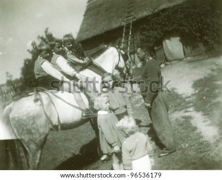 Vintage photo of children riding a horse in farm (fifties)