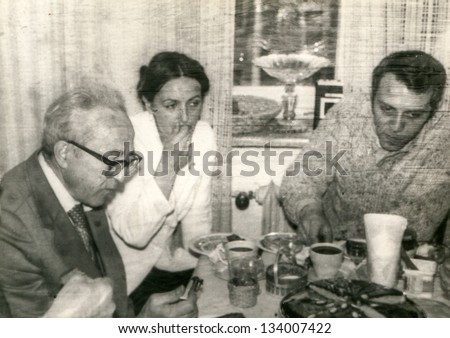 Vintage photo of a young couple with their father/father in law during a family party, seventies