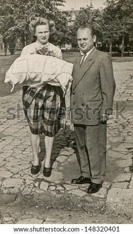 LODZ, POLAND,CIRCA FIFTIES- vintage photo of godparents with a baby in traditional baby\'s sleeping bag for christening, Lodz, Poland, circa fifties