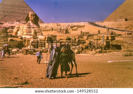 GIZA, EGYPT, CIRCA SIXTIES - vintage photo of female tourist with a camel driver, Giza, Egypt circa sixties