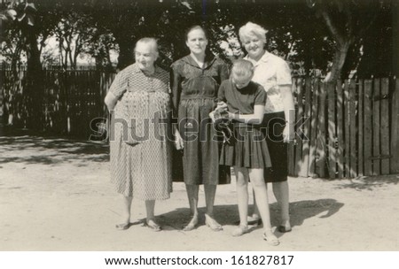 Vintage photo of two grandmothers, mother and daughter with a chicken on farm, fifties