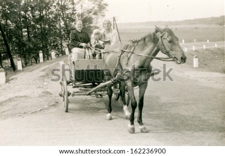 Vintage photo of grandmother, mother and little daughter traveling by horse-drawn carriage, fifties