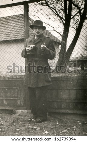 Vintage photo of man with a camera outdoor, fifties