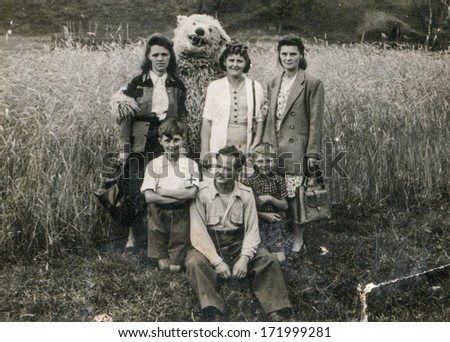 BIELSKO, POLAND, CIRCA 1940s - vintage photo of happy family with a fake bear outdoor