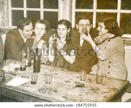 LODZ, POLAND, CIRCA 1950\'s: Vintage photo of young people parting and drinking alcohol together