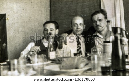 LODZ, POLAND, CIRCA 1950\'s: Vintage photo of men parting and drinking