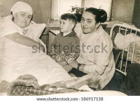 LODZ, POLAND, CIRCA 1950\'s: Vintage photo of mother with little son visiting bedridden grandmother in hospital