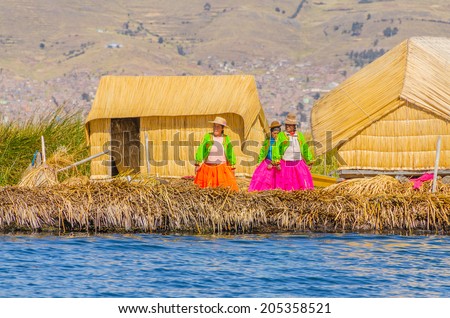 PUNO, PERU, MAY 5, 2014 - Women in traditional attires welcome tourists coming by boats from Puno town to visit floating Uros islands on Lake Titicaca