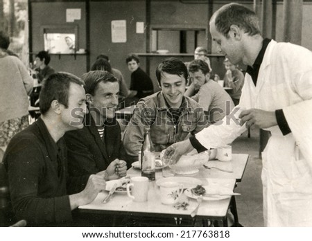 POLAND, CIRCA FIFTIES - Vintage photo of young men and waiter in canteen