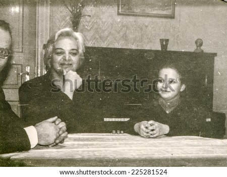 Vintage photo of parents sitting at the table with little girl, fifties