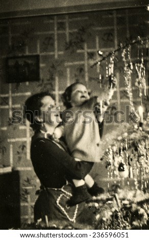 GERMANY, DECEMBER 25, 1938: Mother with a little daughter near Christmas tree
