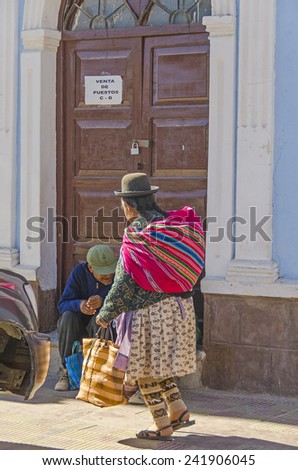 UYUNI, BOLIVIA, MAY 15, 2014:  Local woman in traditional attire walks at Plaza Arce