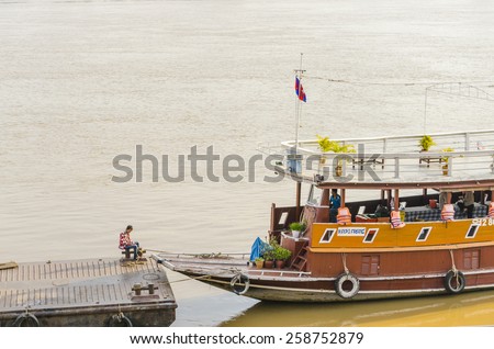 PHNOM PENH, CAMBODIA, JANUARY 2, 2013: Local man seats near the boat on pier in International port waiting for tourists